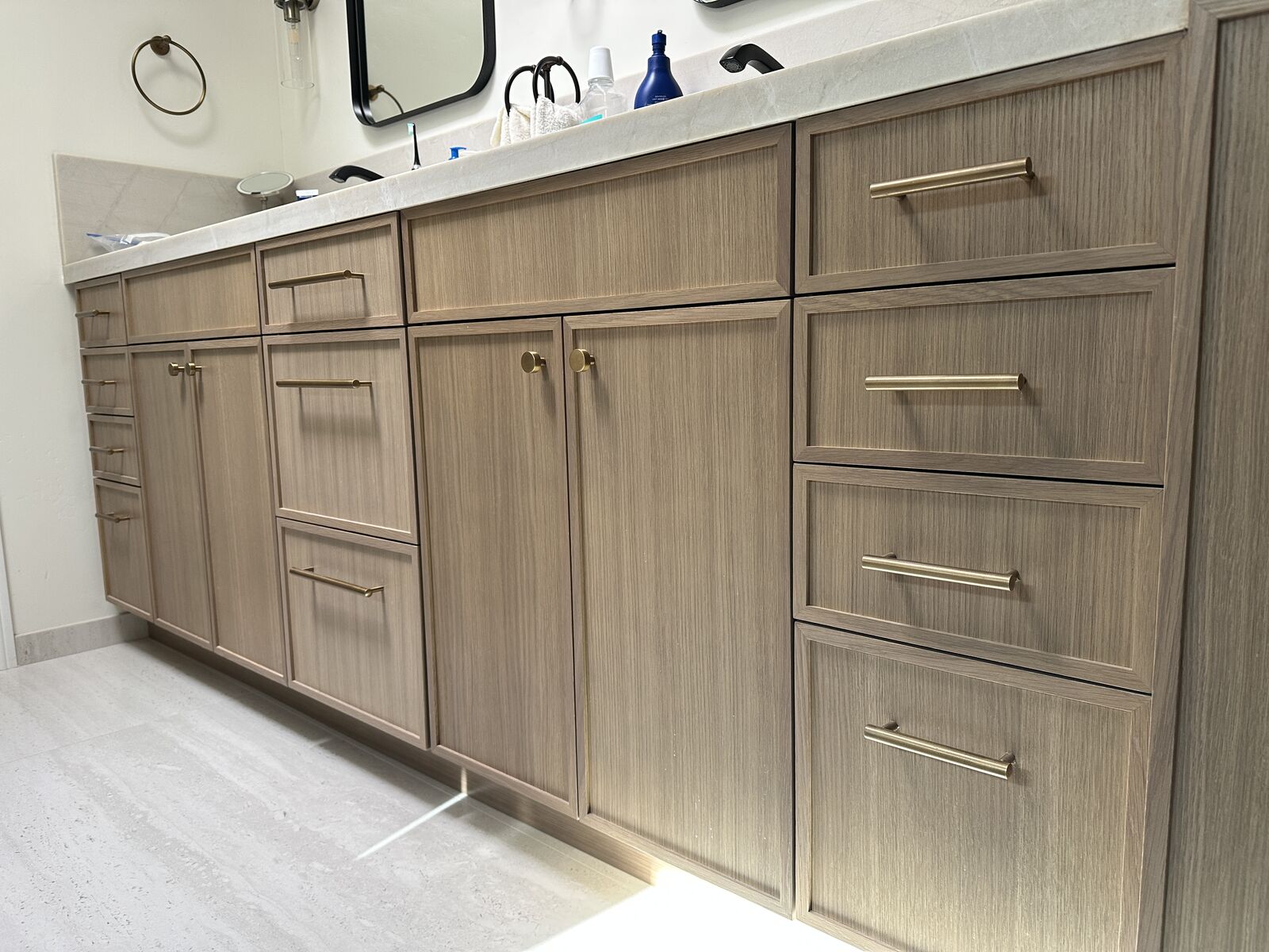 Custom wood-grain cabinetry with brushed brass pulls by PRDI