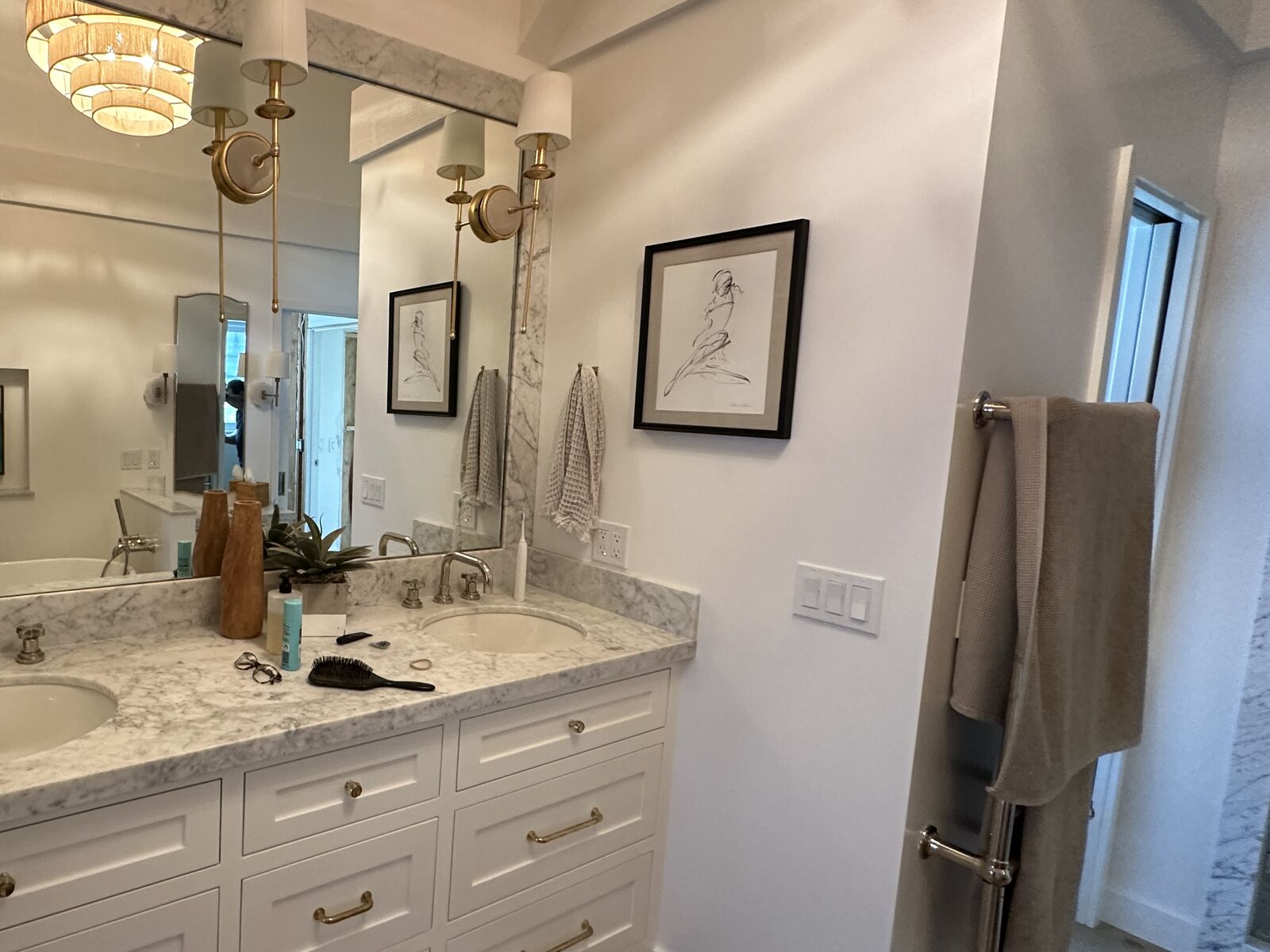 Completed PRDI bathroom with white shaker double vanity, marble countertop, and brass sconces