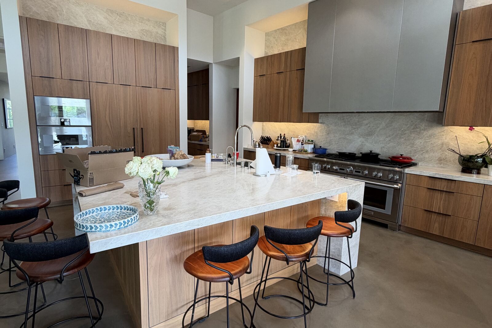 Completed PRDI modern kitchen with stone waterfall island, walnut cabinetry, and counter seating