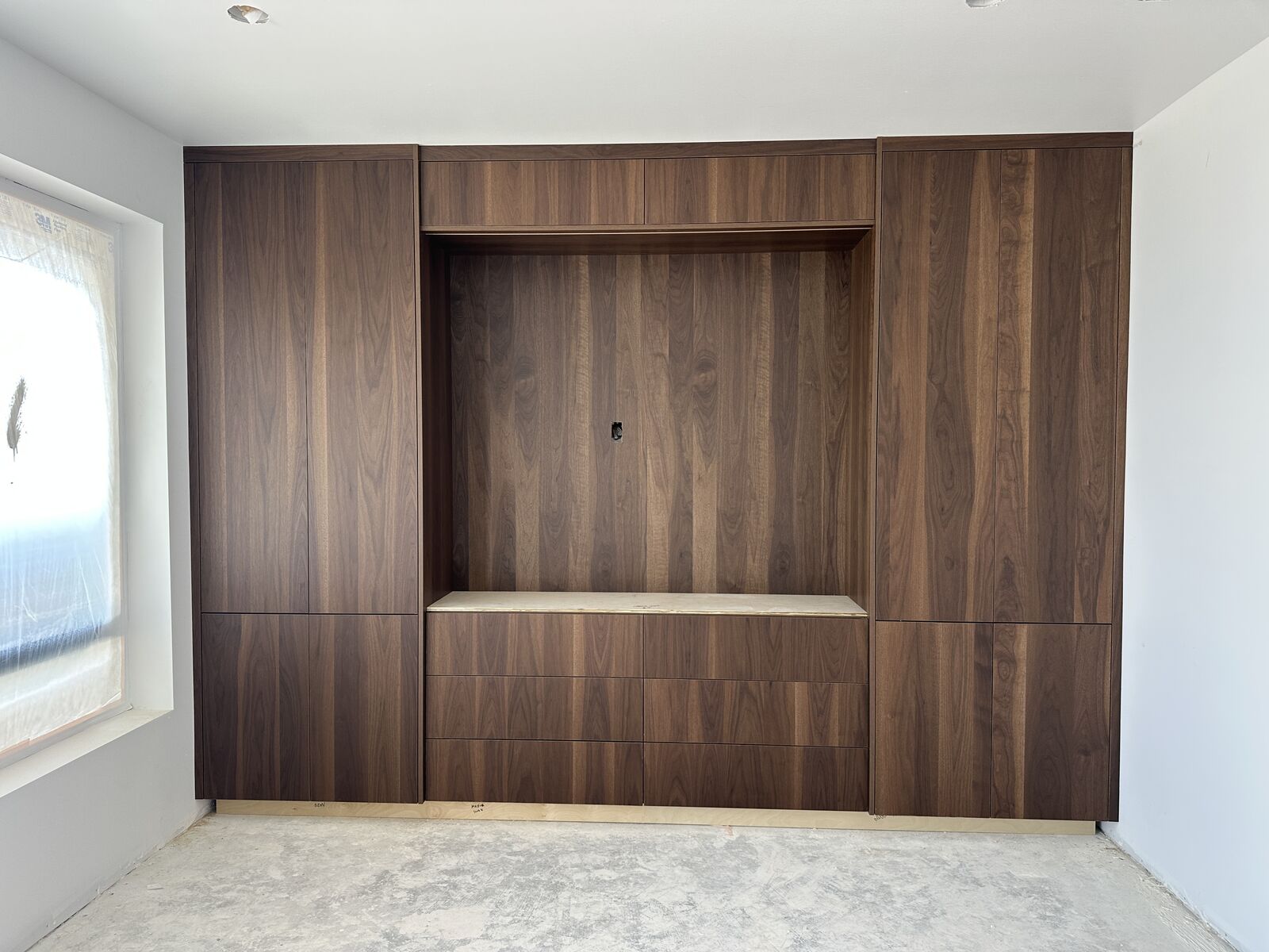 Custom walnut built-in wall cabinetry with recessed media niche by PRDI